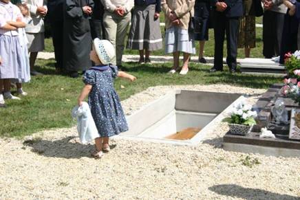 Une petite fille montre du doigt la tombe de l’abbé Joseph Vérité